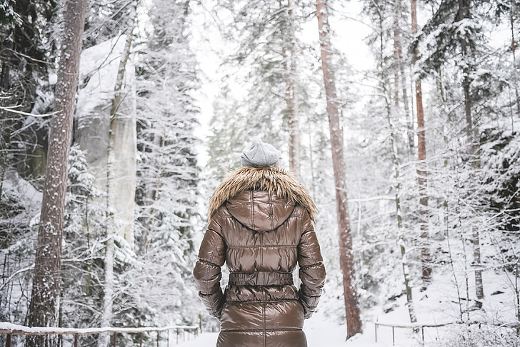 A woman in a jacket standing in a snowy forest. The coats and jackets industry is projected to grow around 2.7% in the next five years.
