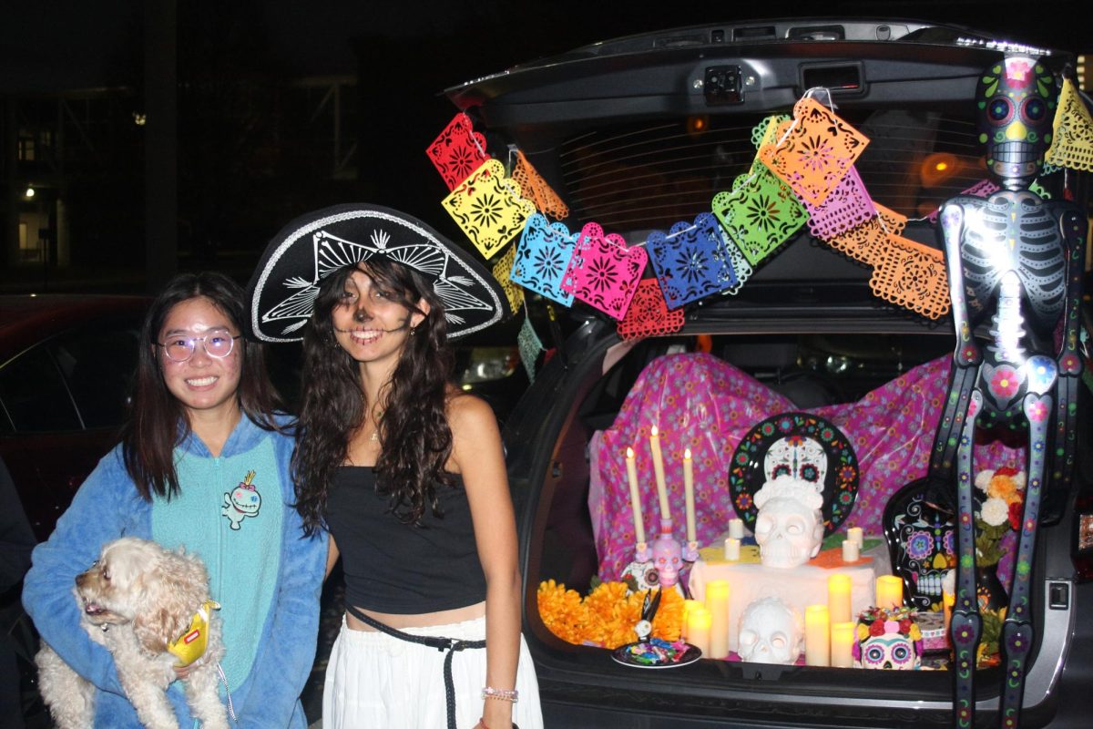 Seniors Winnie Chen and Zoe Sauvagnargues posing in front of their Día de Muertos themed trunk. 