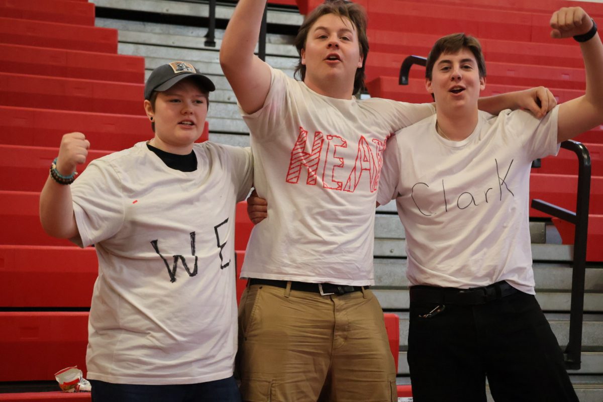 Group of students cheering for senior Adam Clark. Their shirts saying, “We Heart Clark”.